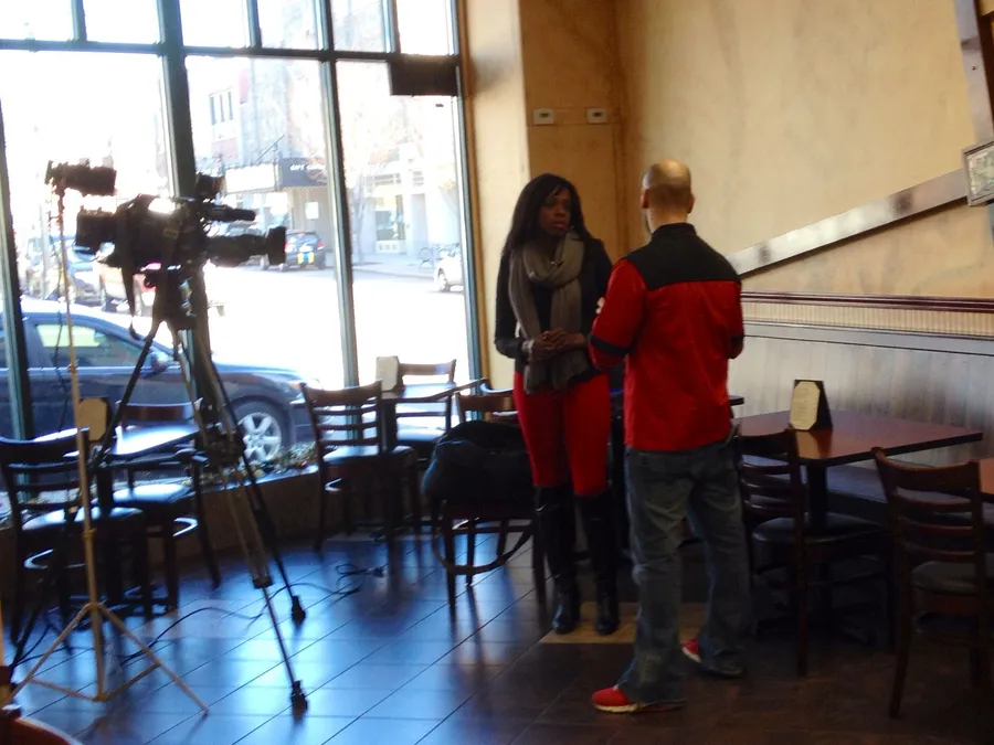 A Channel 5 Chronicle reporter interviews the owner of To Beirut Bistro in Norwood while a camera on a tripod rolls