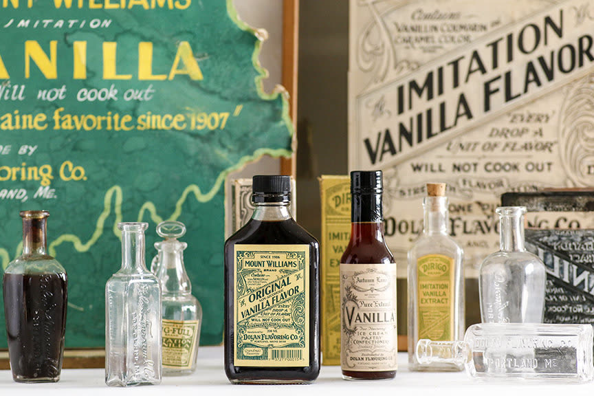 Dolan vanilla bottles and antique flavoring bottles in front of vintage signage